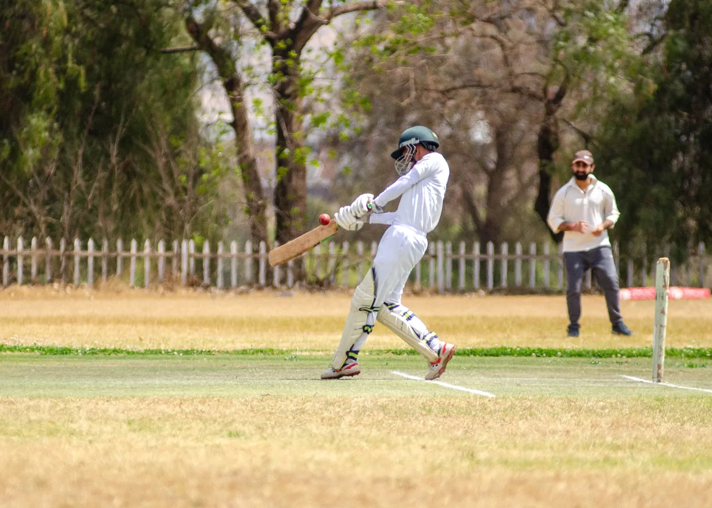 Cricketer preparing to bat during an outdoor match
